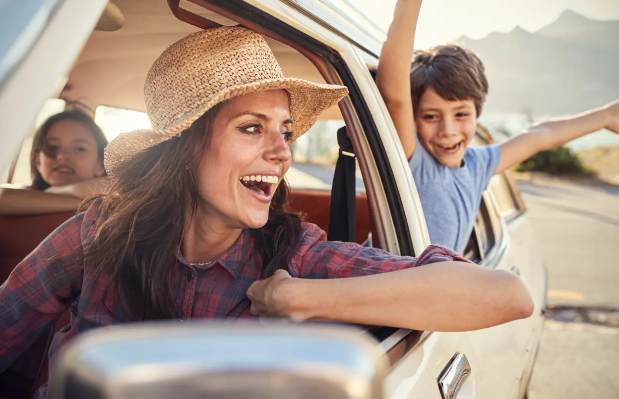 Mutter mit Kindern gut gelaunt im Auto unterwegs