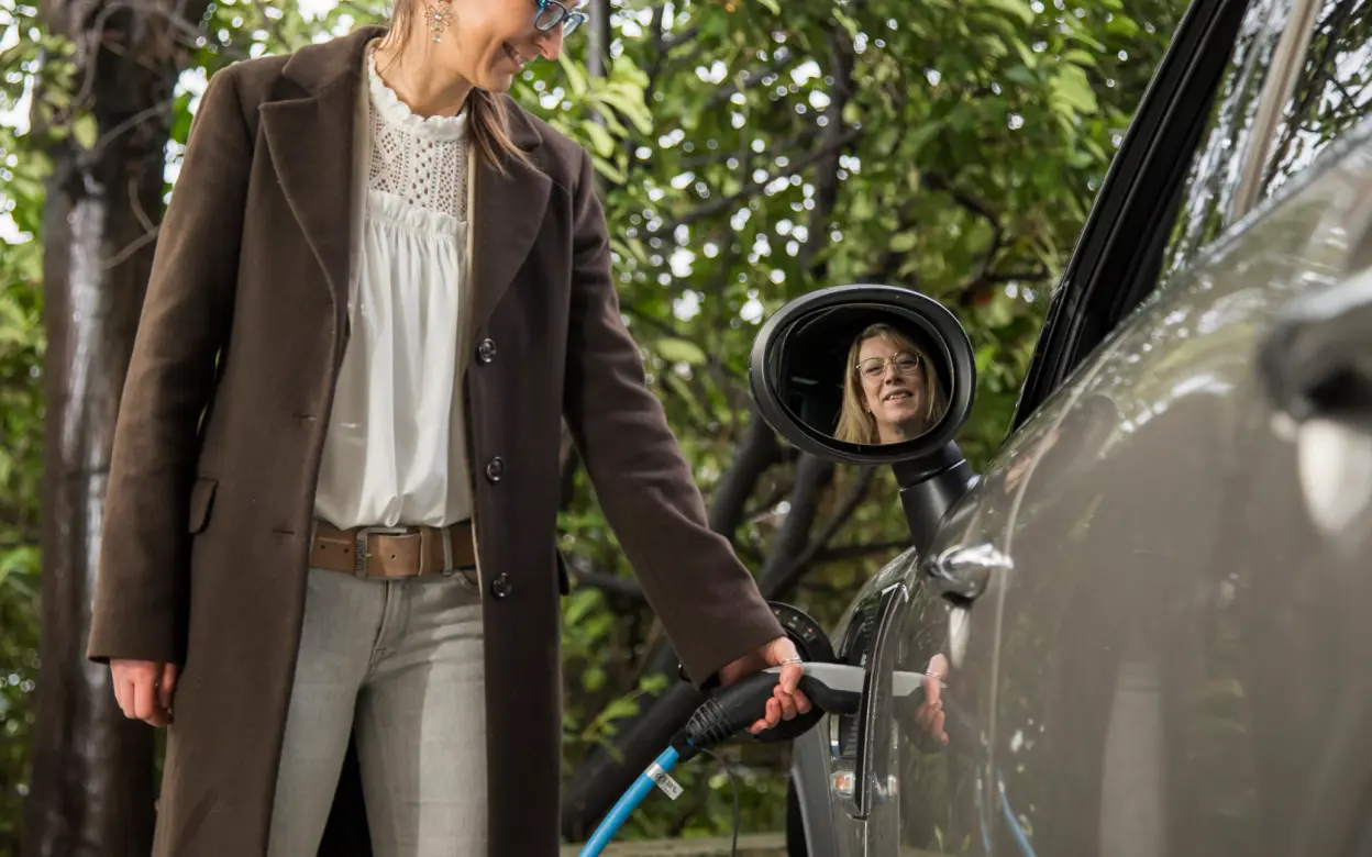 Frau lädt E-Auto