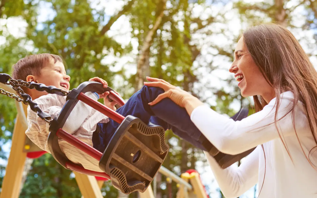 Mutter und Kind spielen auf Schaukel