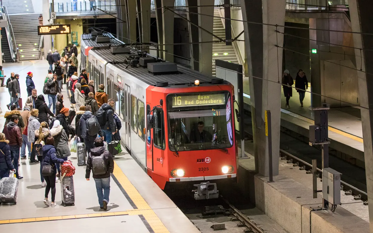 An einem Bahnsteig stehen viele Menschen und eine haltende Bahn.