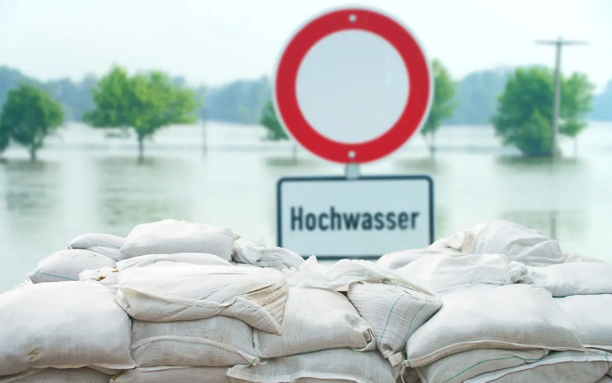 Hochwasser mit Schild und Sandsäcken.