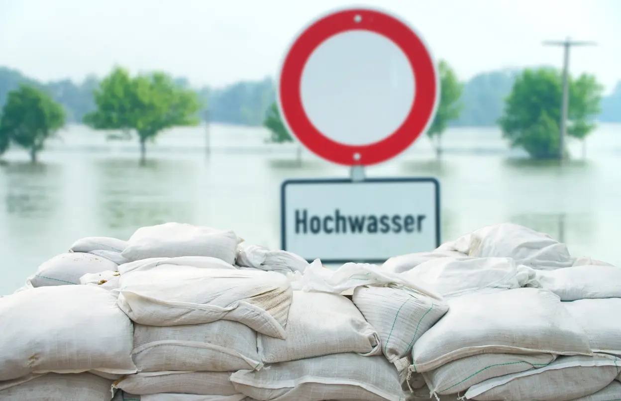 Hochwasser mit Schild und Sandsäcken.