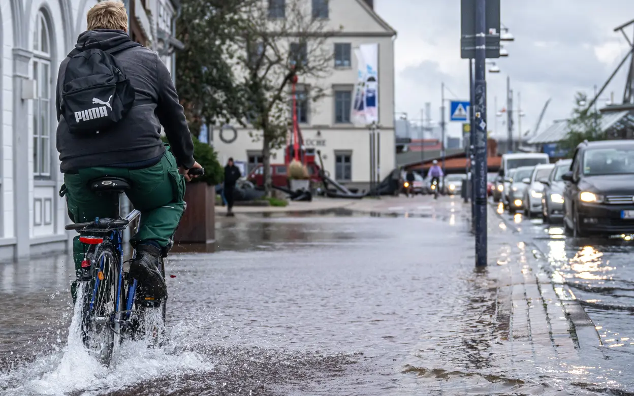 Mann fährt mit Fahrrad durch Hochwasser.