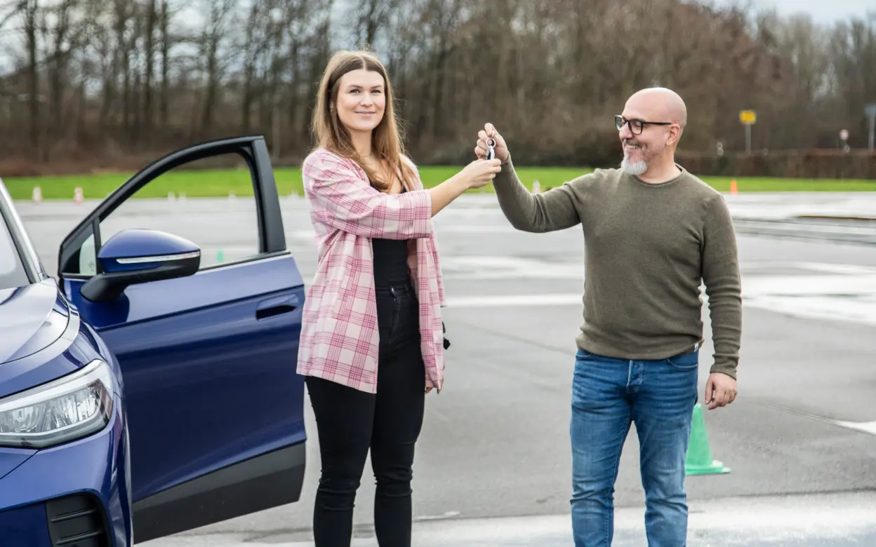 Ein Mann übergibt einer jungen Frau den Autoschlüssel.