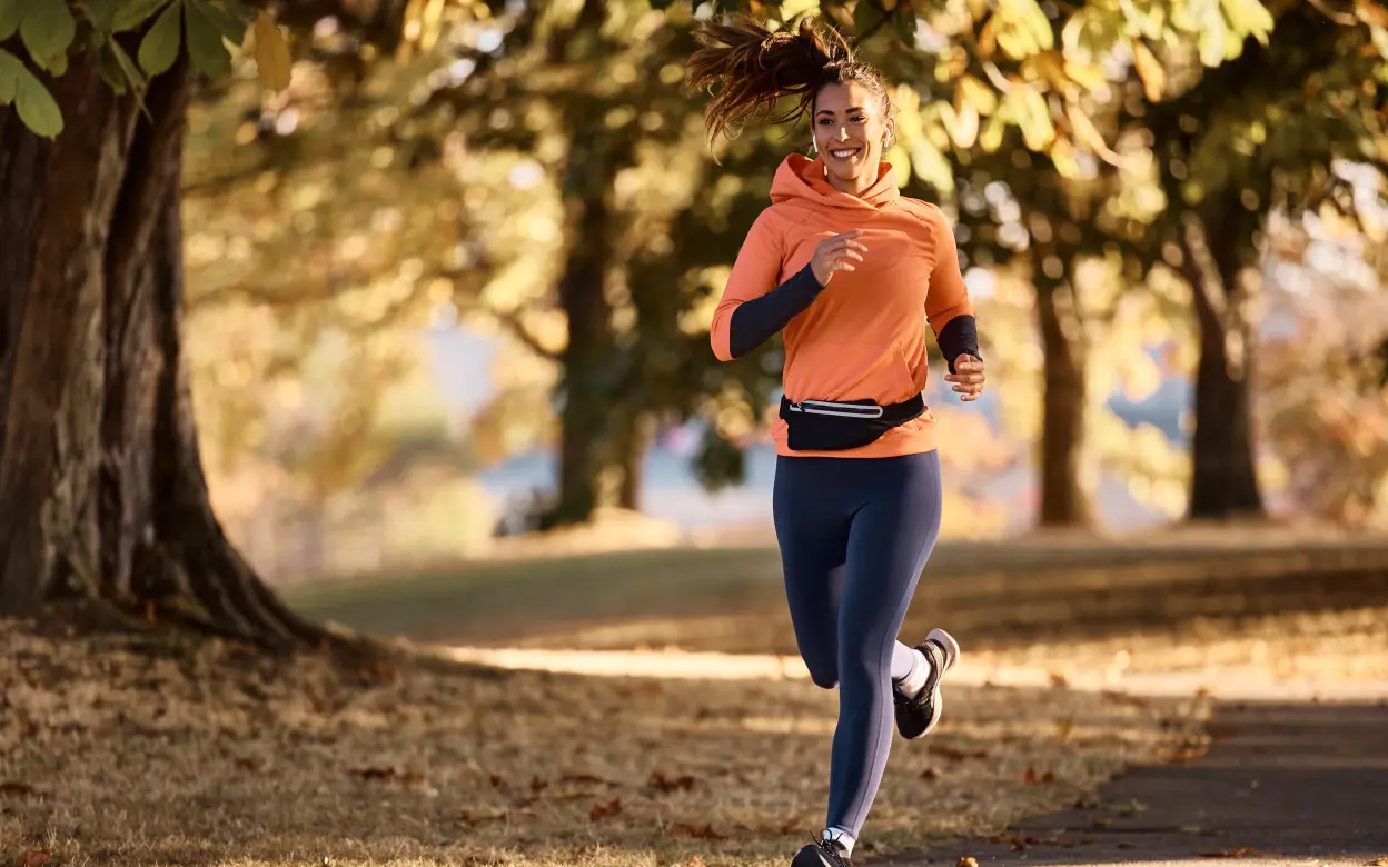 Frau joggt gut gelaunt im herbstlichen Park