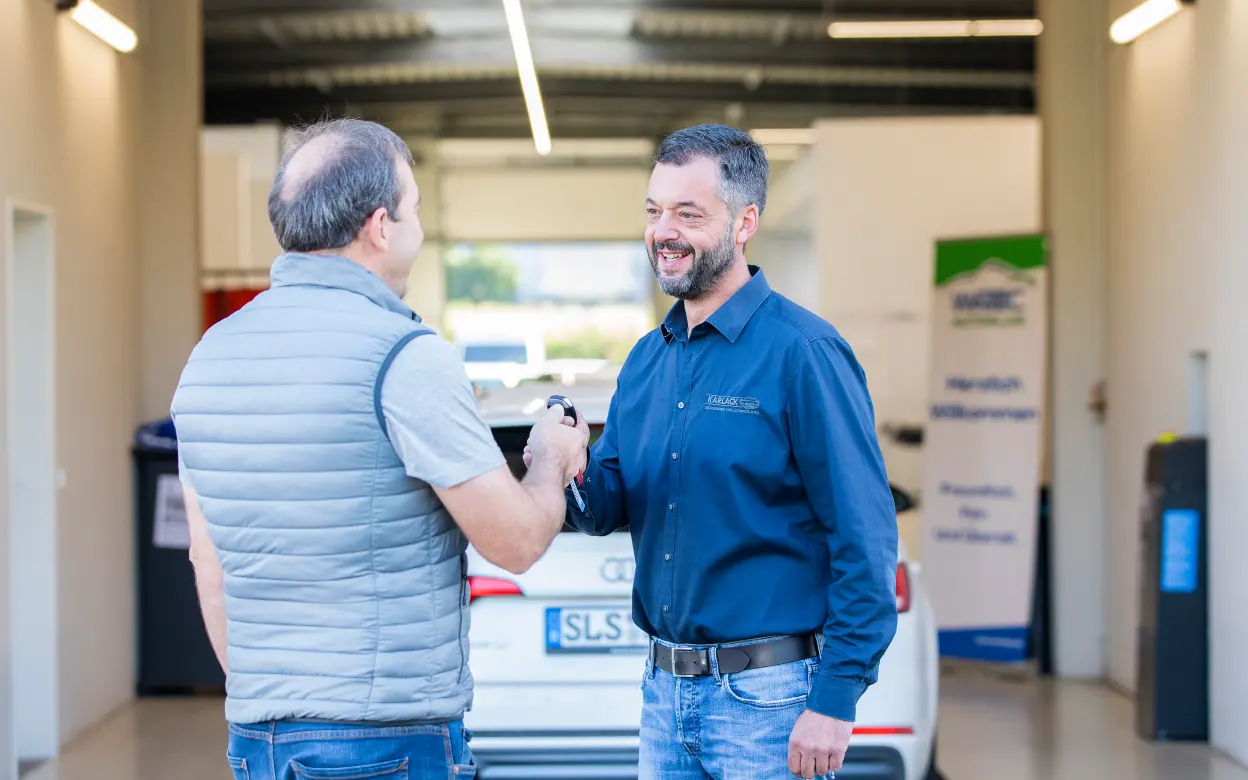 Verkäufer übergibt Autoschlüssel an Käufer 
