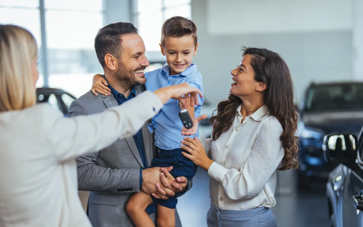 Familie bekommt den Schlüssel nach Autokauf überreicht