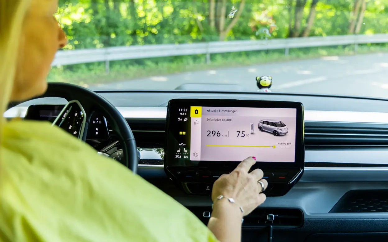 Eine Frau sitzt in einem E-Auto und bedient das Display 