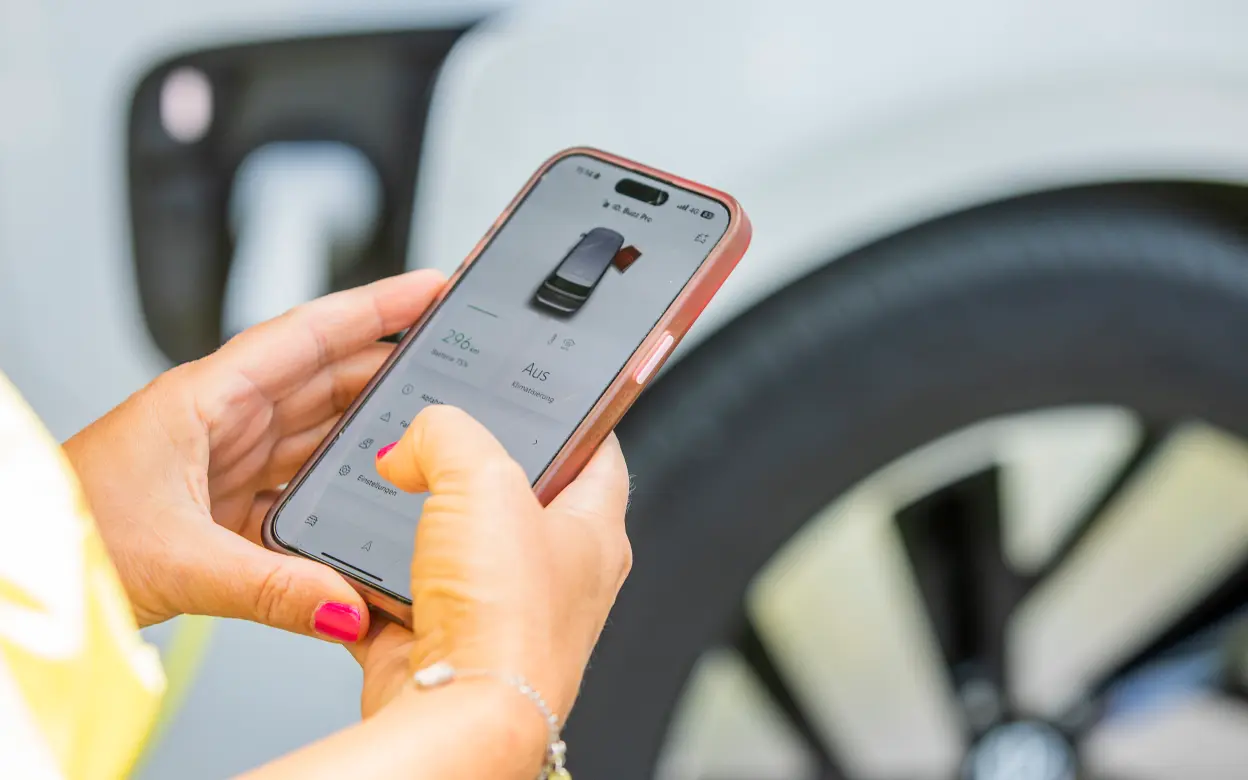 Frau prüft die E-Auto-Reichweite via Smartphone-App