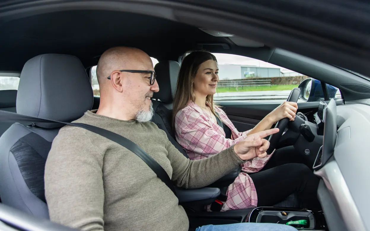 Mann und Frau machen eine Probefahrt im E-Auto