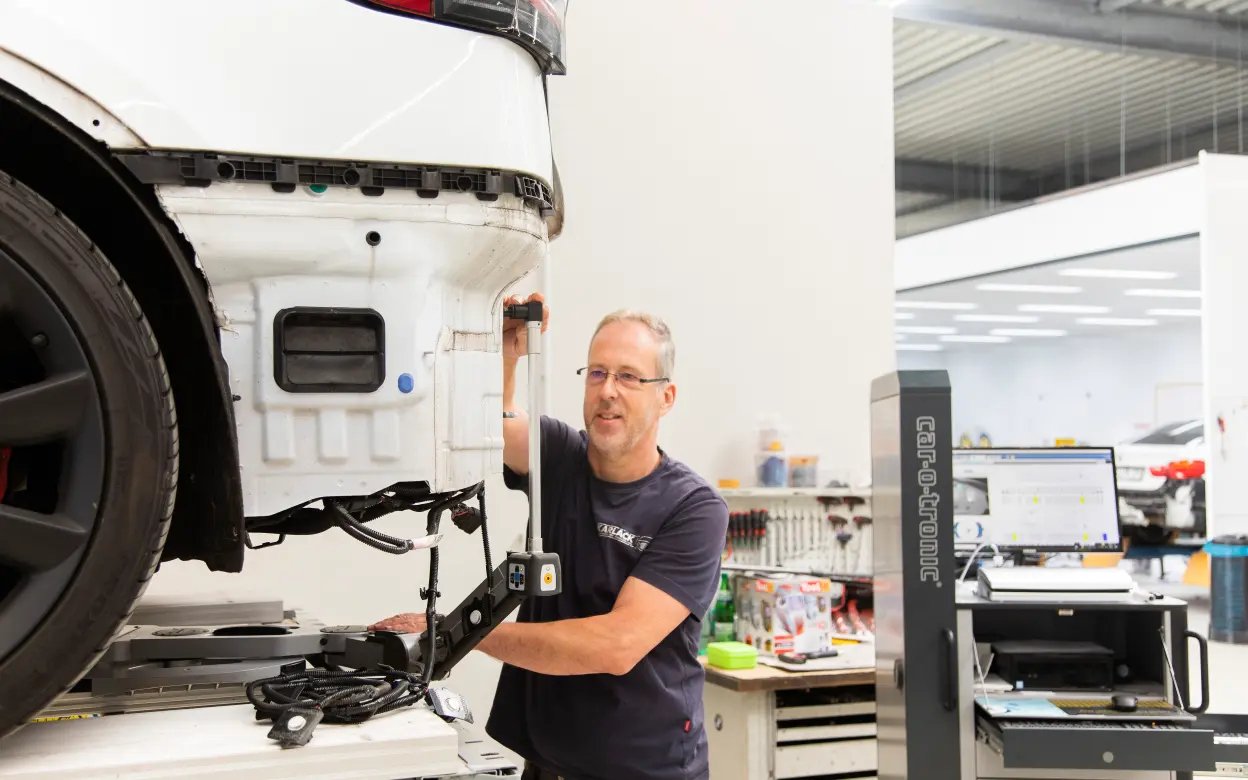 Mechaniker repariert E-Auto in Kfz-Werkstatt