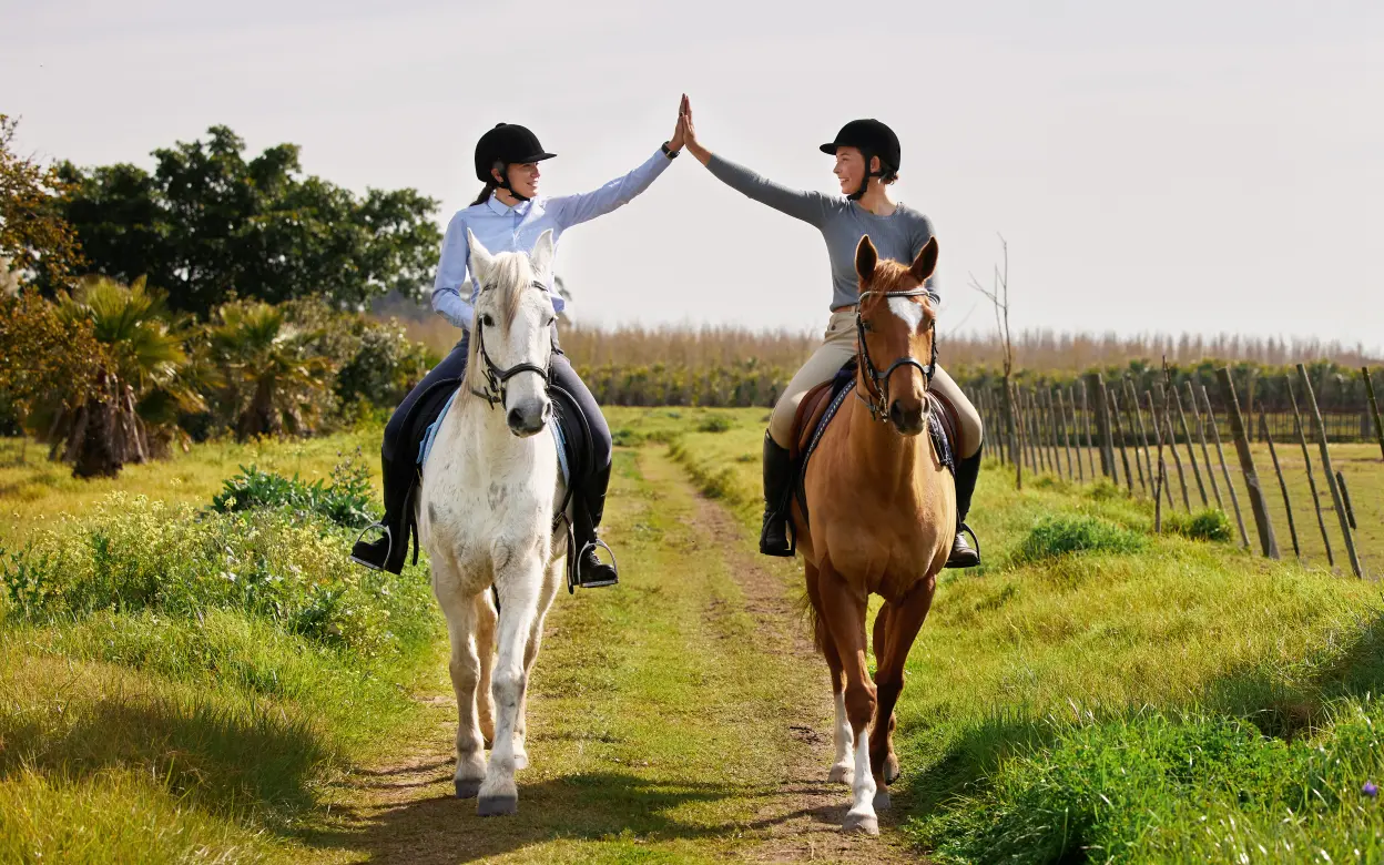 Zwei Reiterinnen geben sich ein High Five
