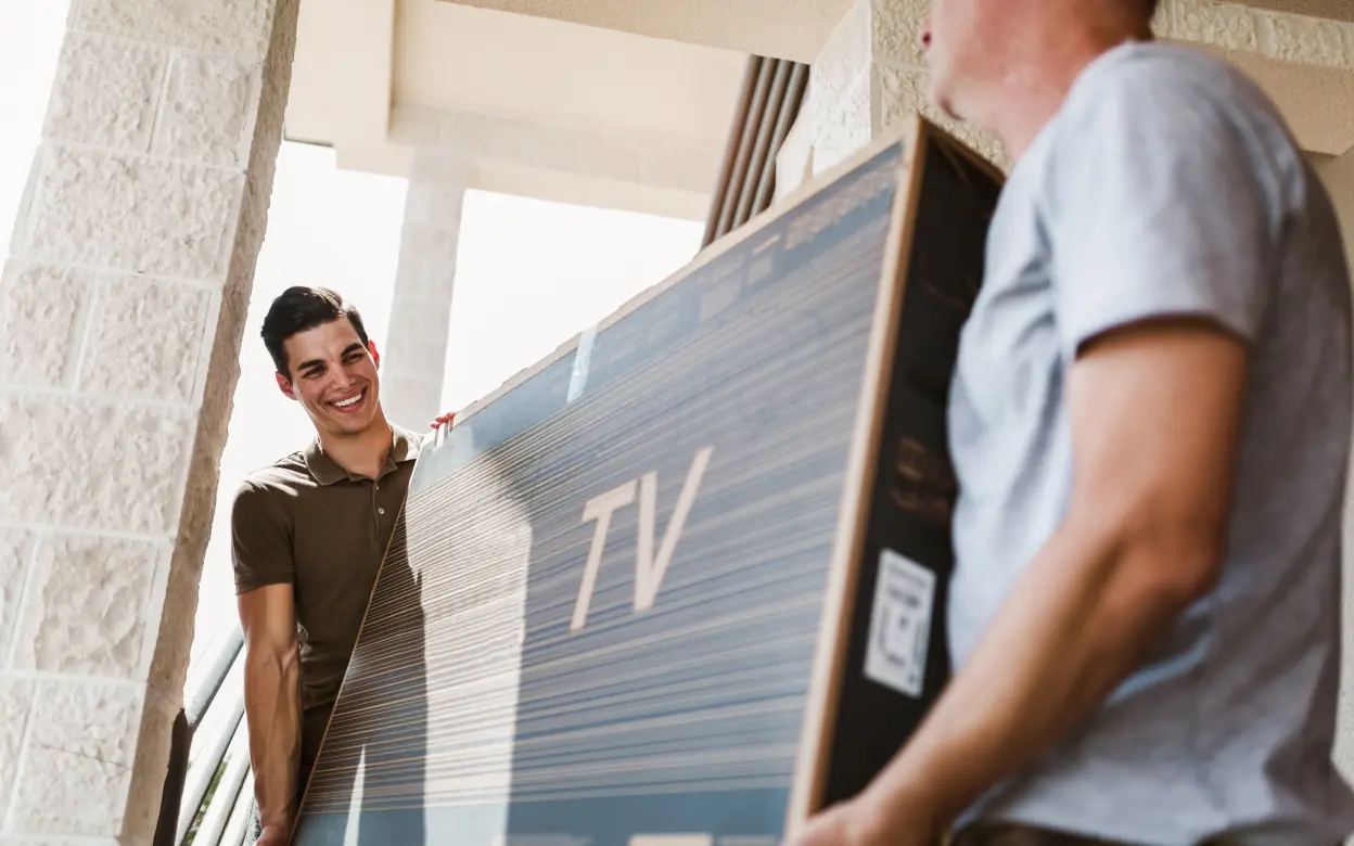 Zwei Männer tragen Fernseher im Karton