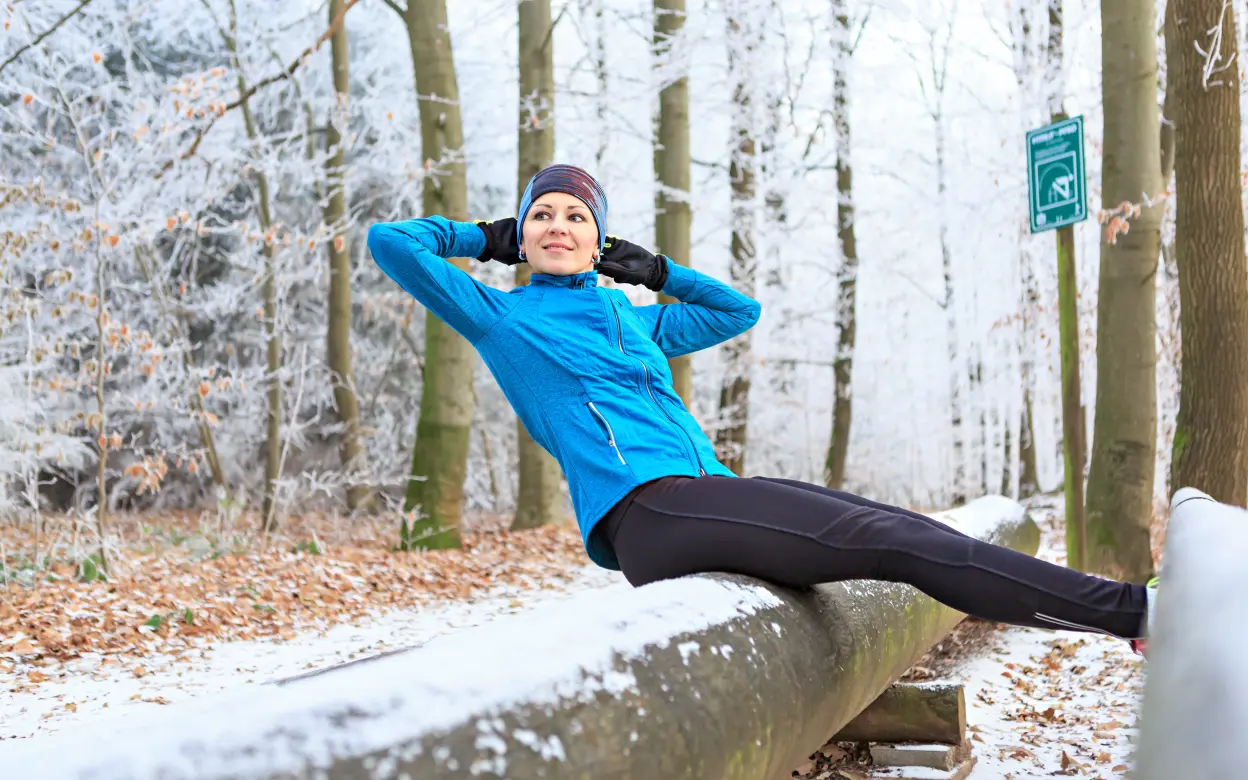 Läuferin dehnt sich im verschneiten Wald