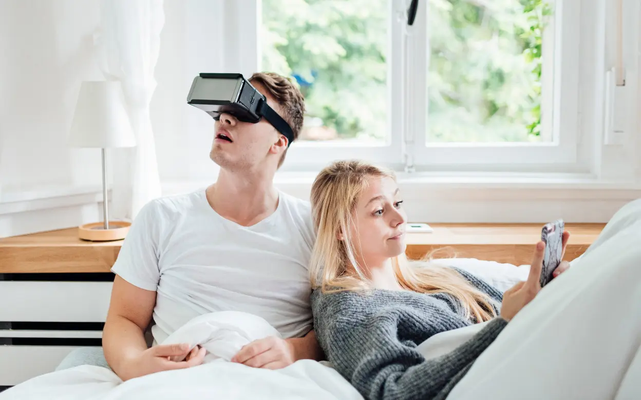 Junges Paar sitzt auf Sofa und nutzt Virtual Reality Brille