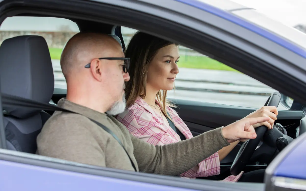 Mann erklärt Autofahrerin etwas während des Begleiteten Fahrens