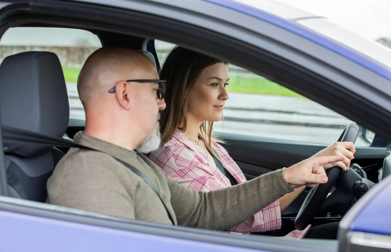Mann erklärt Autofahrerin etwas während des Begleiteten Fahrens