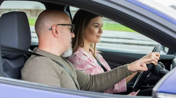 Mann erklärt Autofahrerin etwas während des Begleiteten Fahrens