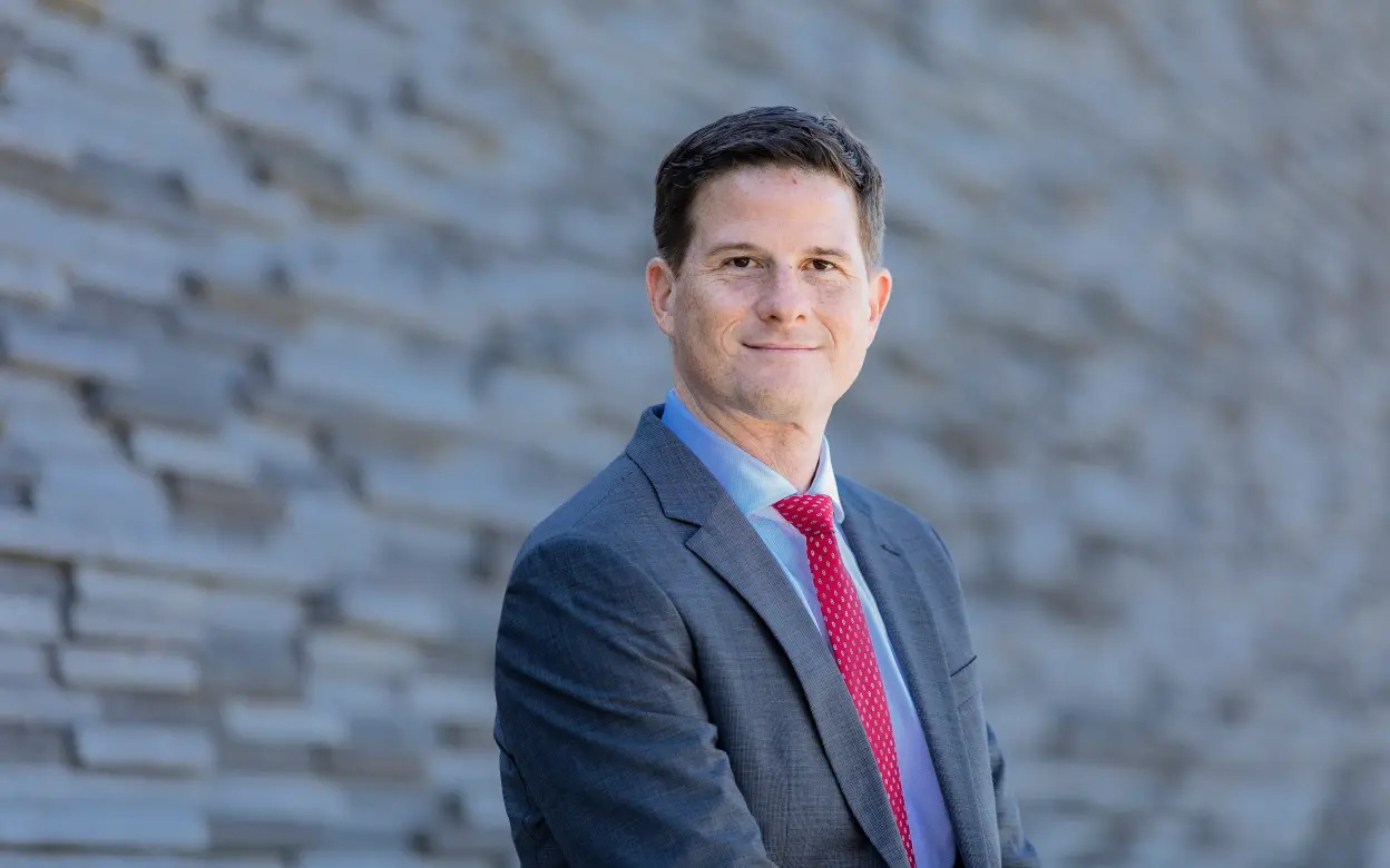 Vorstand Dr. Michael Zons steht vor einer Steinwand