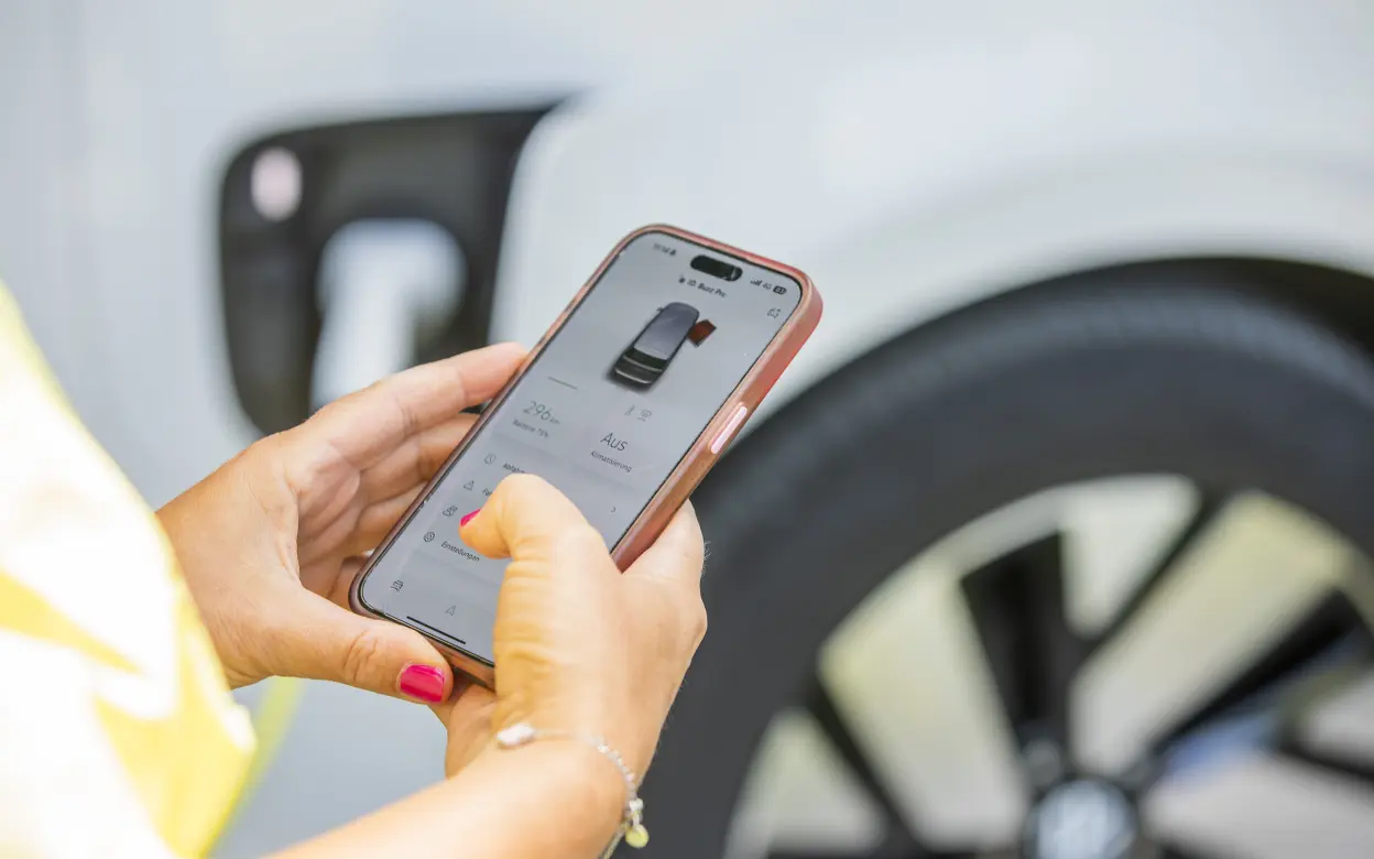 Frau nutzt E-Auto-App auf dem Smartphone