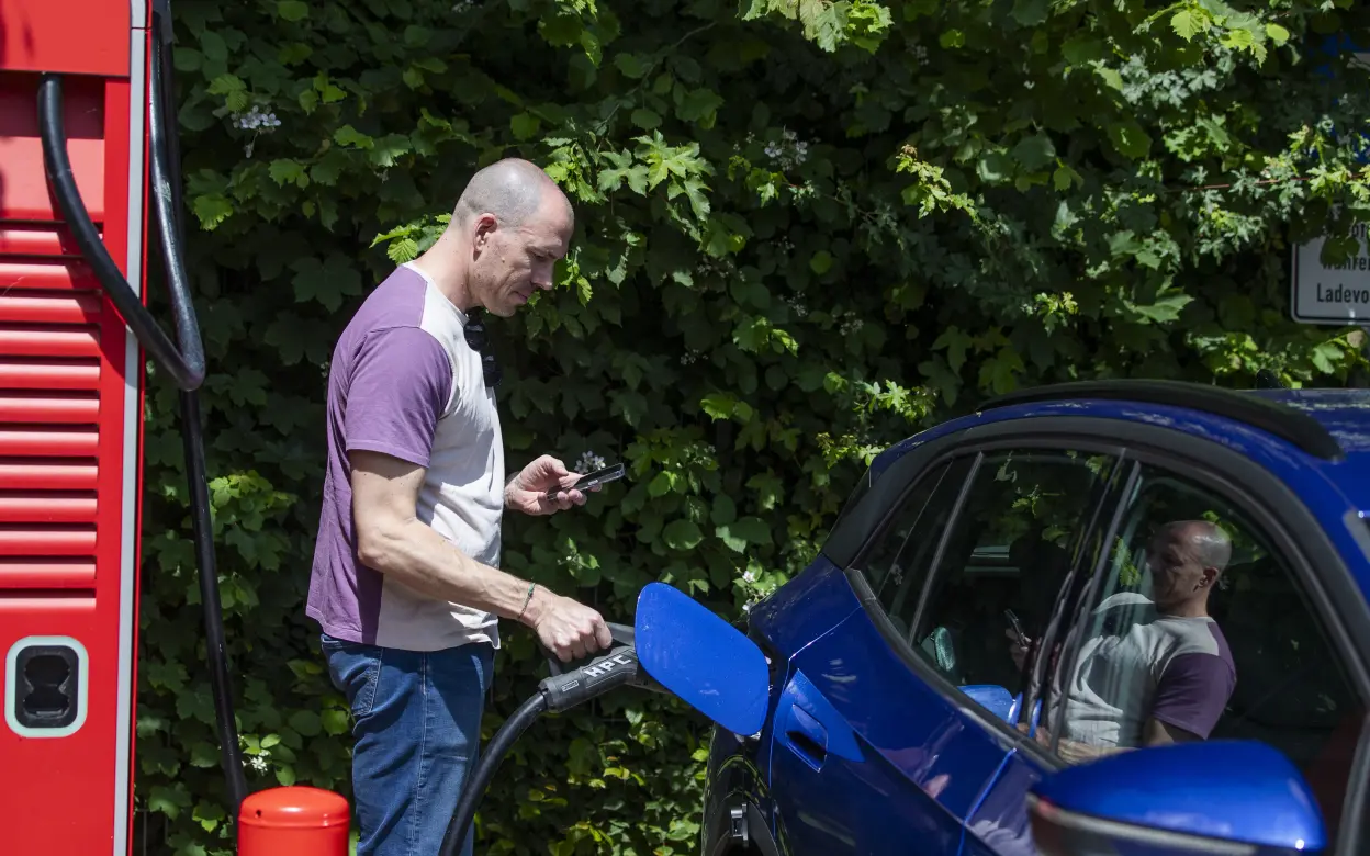 Mann lädt E-Auto an Ladestation