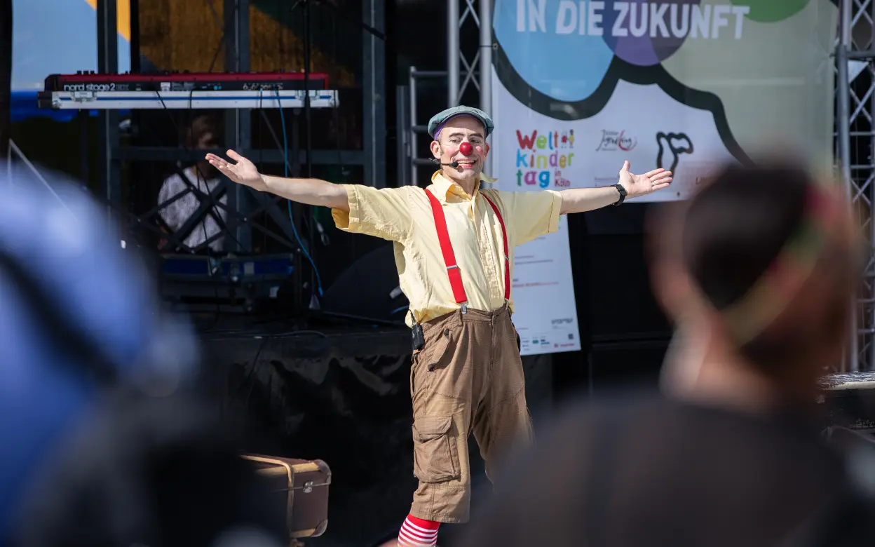 Clown Olli begeistert Besucher:innen auf der Bühne beim Weltkindertag-Fest
