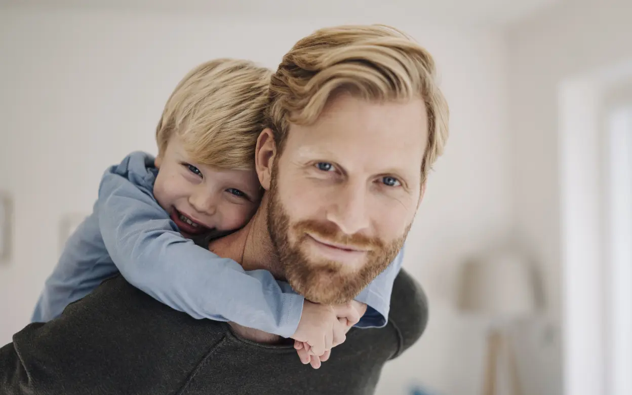 Ein Vater trägt seinen Sohn Huckepack