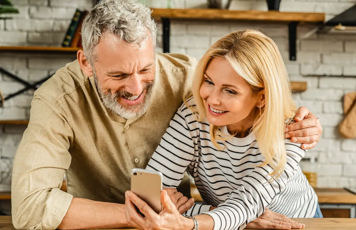 Paar schaut in Küche gemeinsam aufs Handy