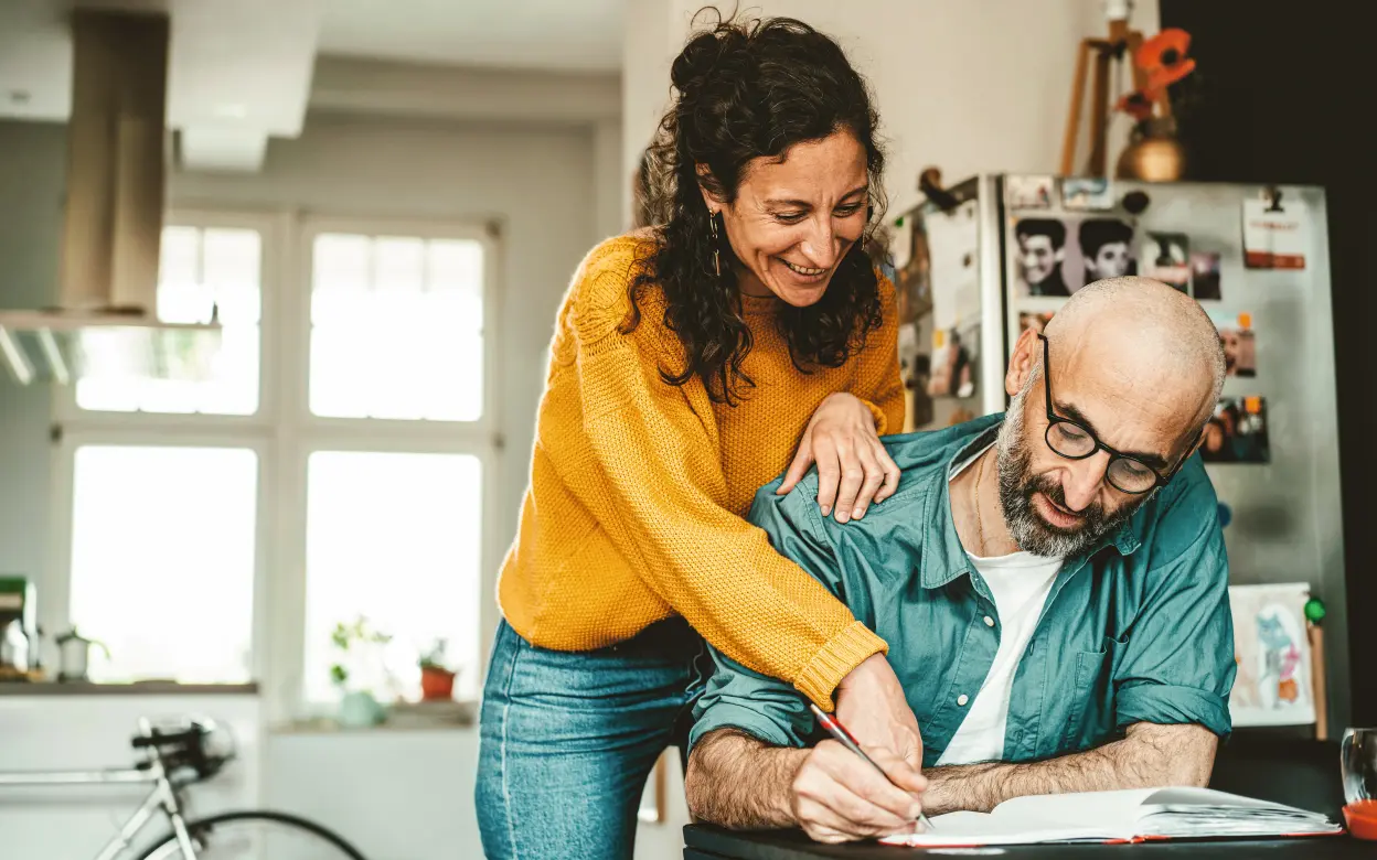 Ein Mann und eine Frau schreiben zusammen in ein Buch.