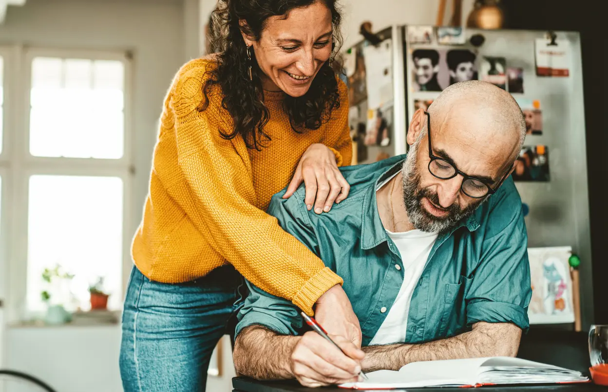Ein Mann und eine Frau schreiben zusammen in ein Buch.