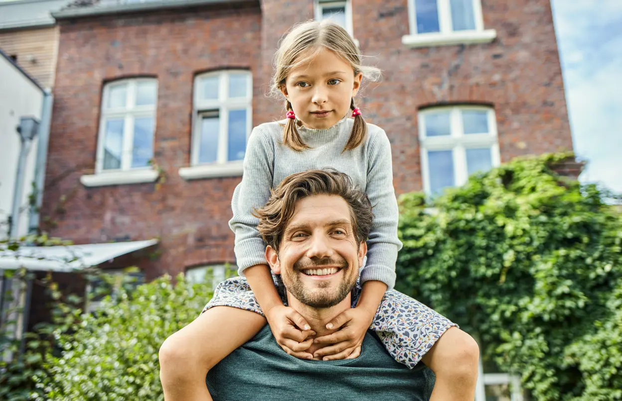 Ein Mann trägt ein Kind auf den Schultern.