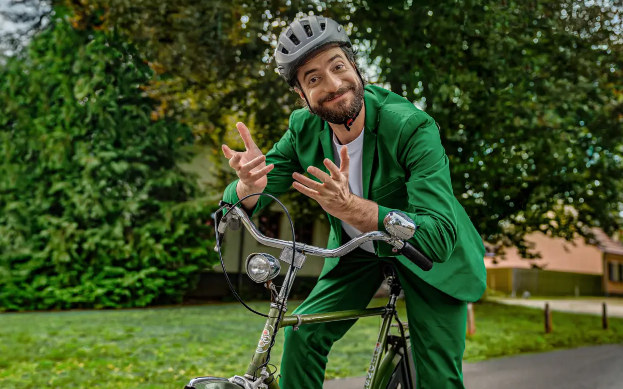Ein Mann sitzt auf einem Fahrrad und schaut den Betrachter fragend und zugleich freundlich einladend an.