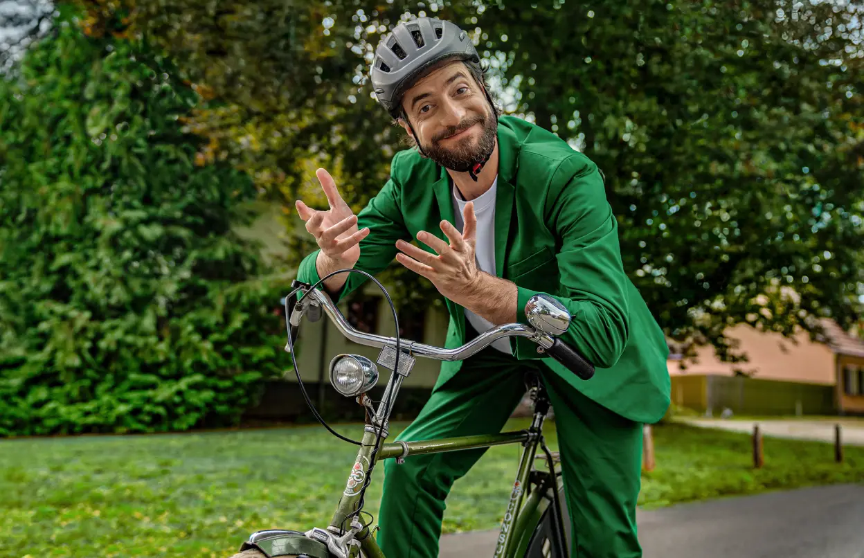 Ein Mann sitzt auf einem Fahrrad und schaut den Betrachter fragend und zugleich freundlich einladend an.