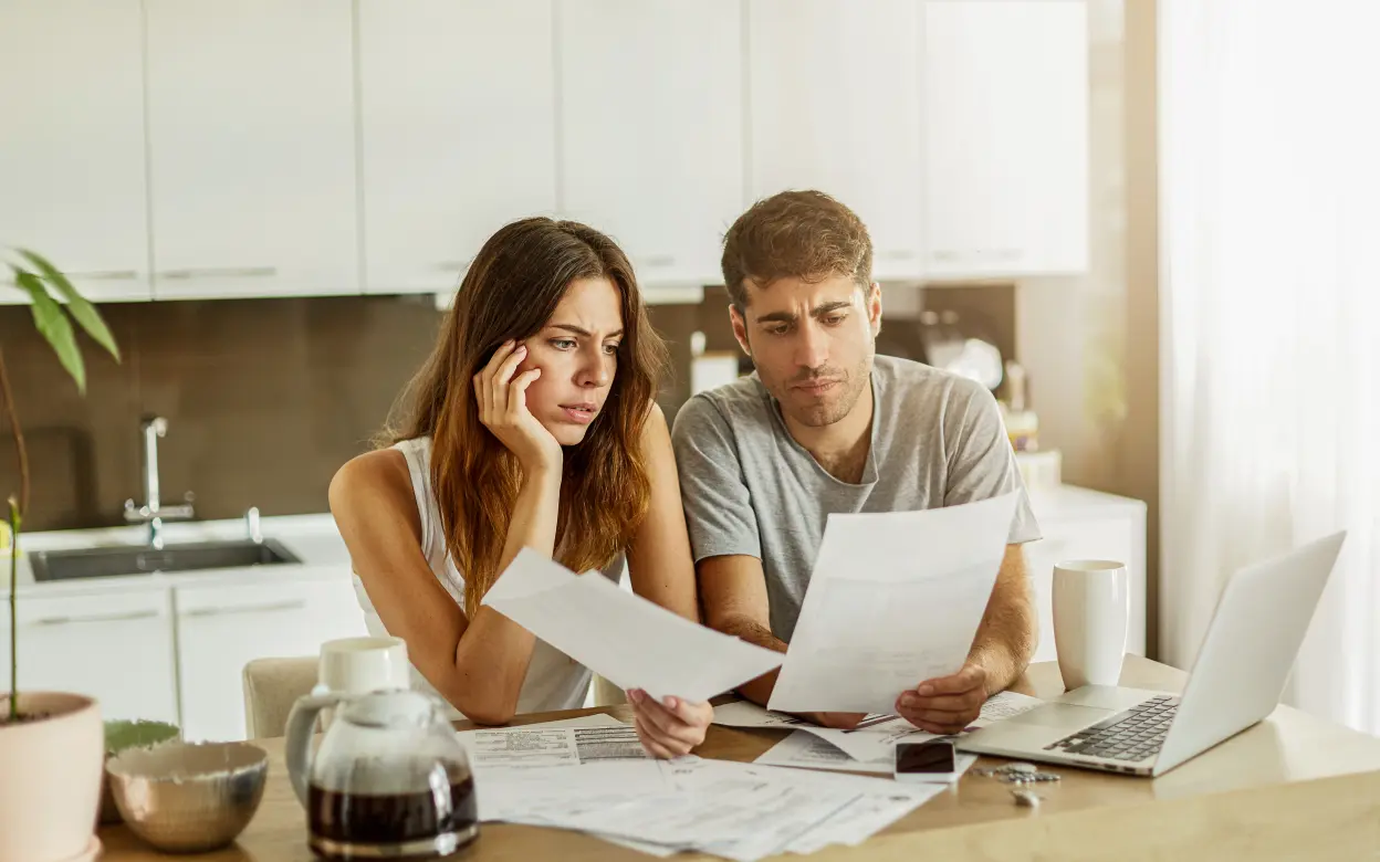 Frau und Mann sichten konzentriert ein Dokument am Küchentisch