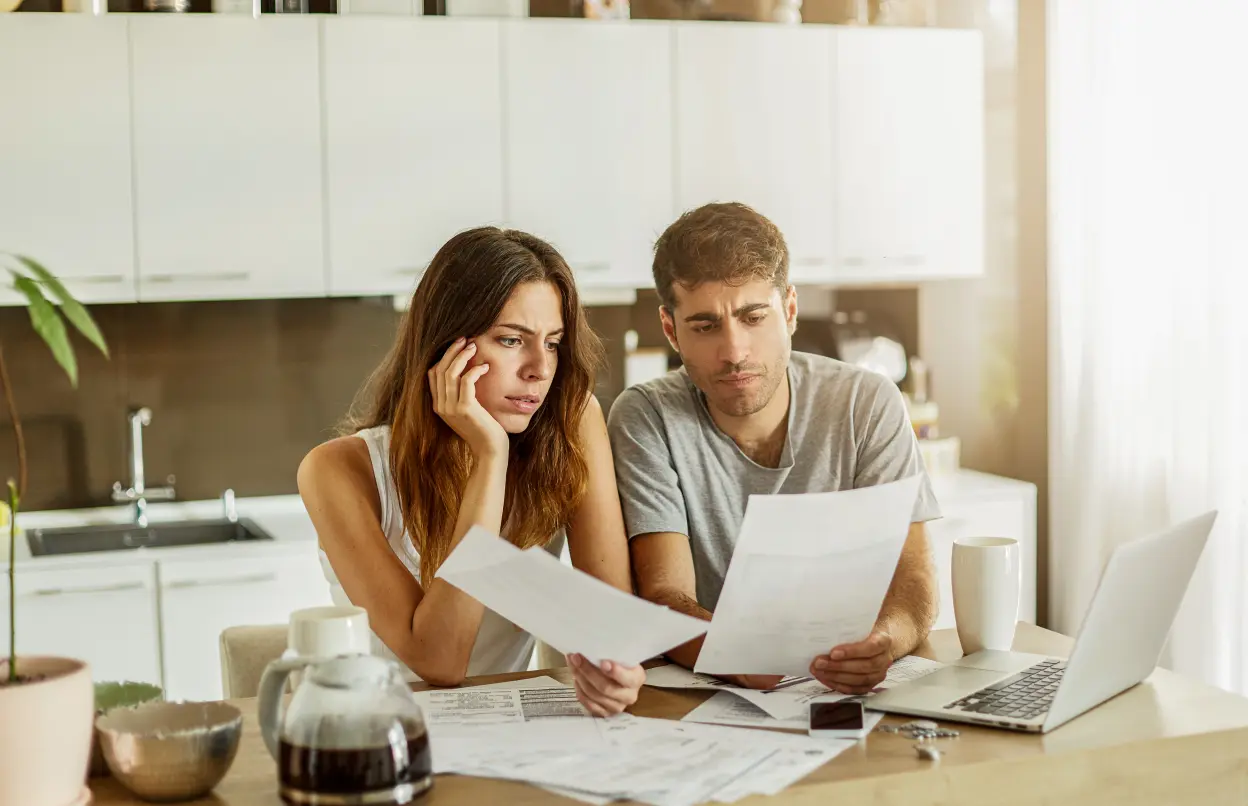 Frau und Mann sichten konzentriert ein Dokument am Küchentisch