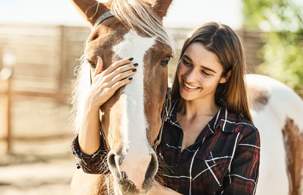 Lächelnde Frau streichelt ihr Pferd