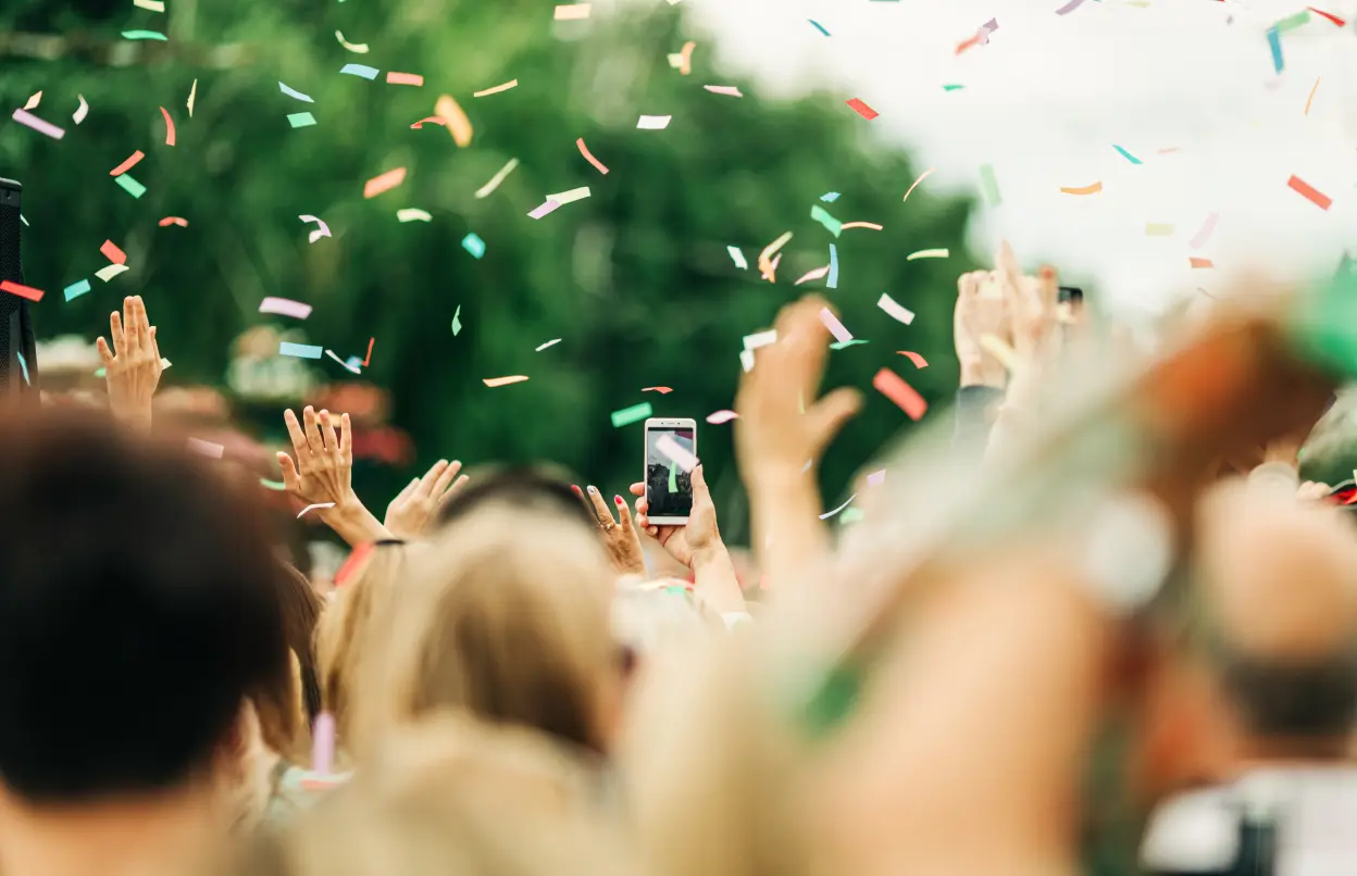 Viele Menschen stehen zusammen und es fliegt Konfetti durch die Luft.