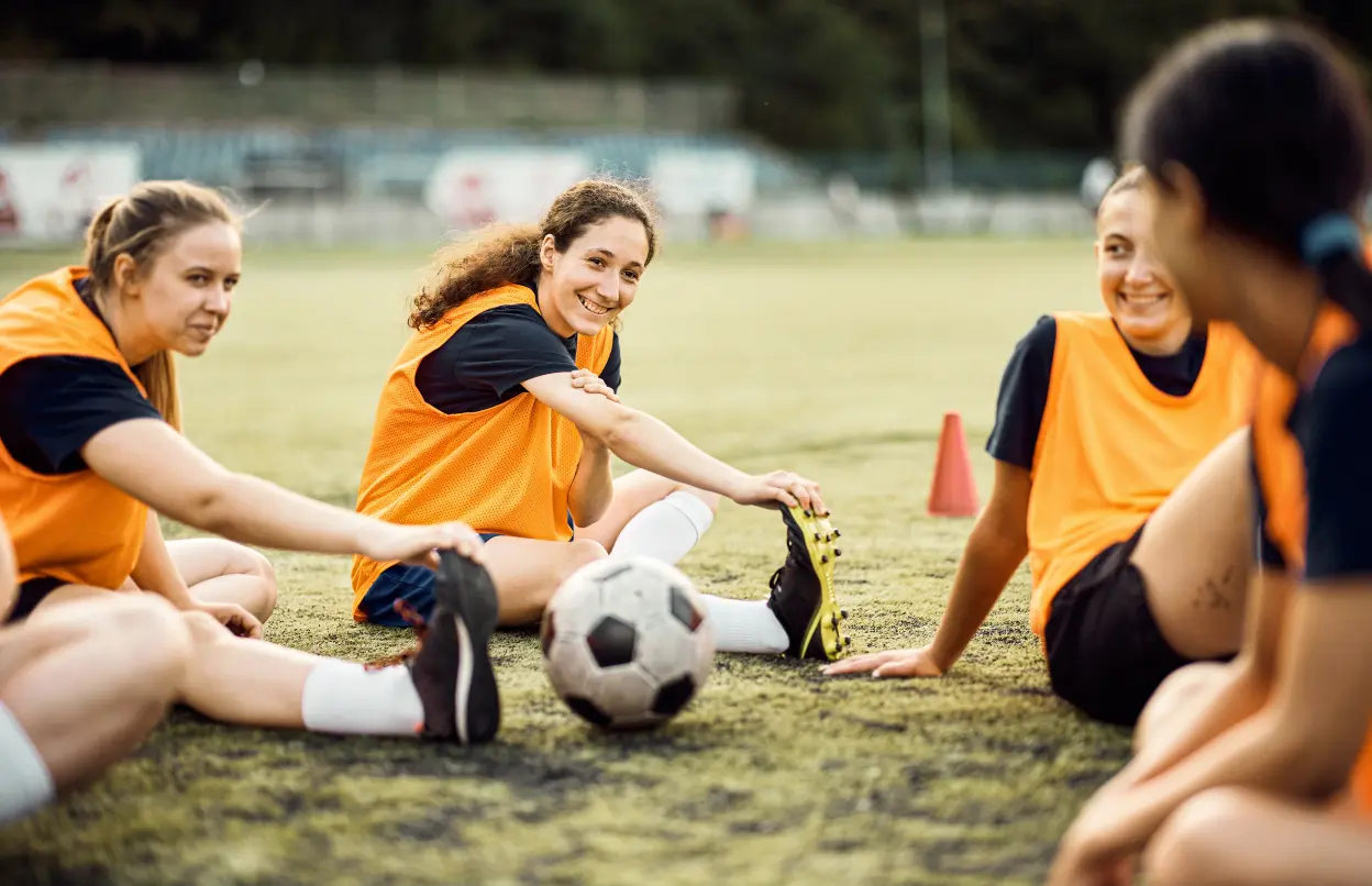 Eine Gruppe Frauen dehnt sich auf einem Fussballplatz.