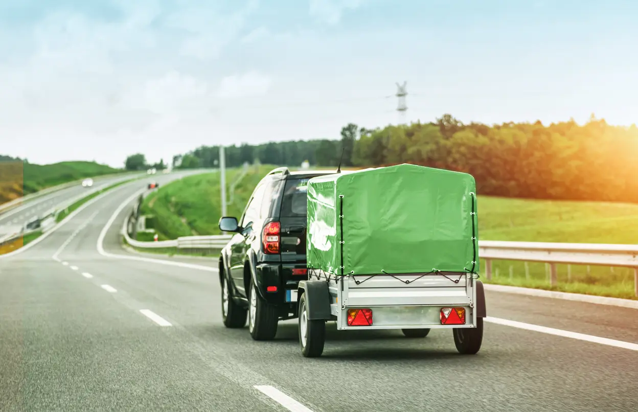 Ein Auto zieht einen grünen Anhänger.