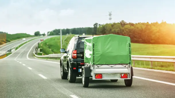 Ein Auto zieht einen grünen Anhänger.