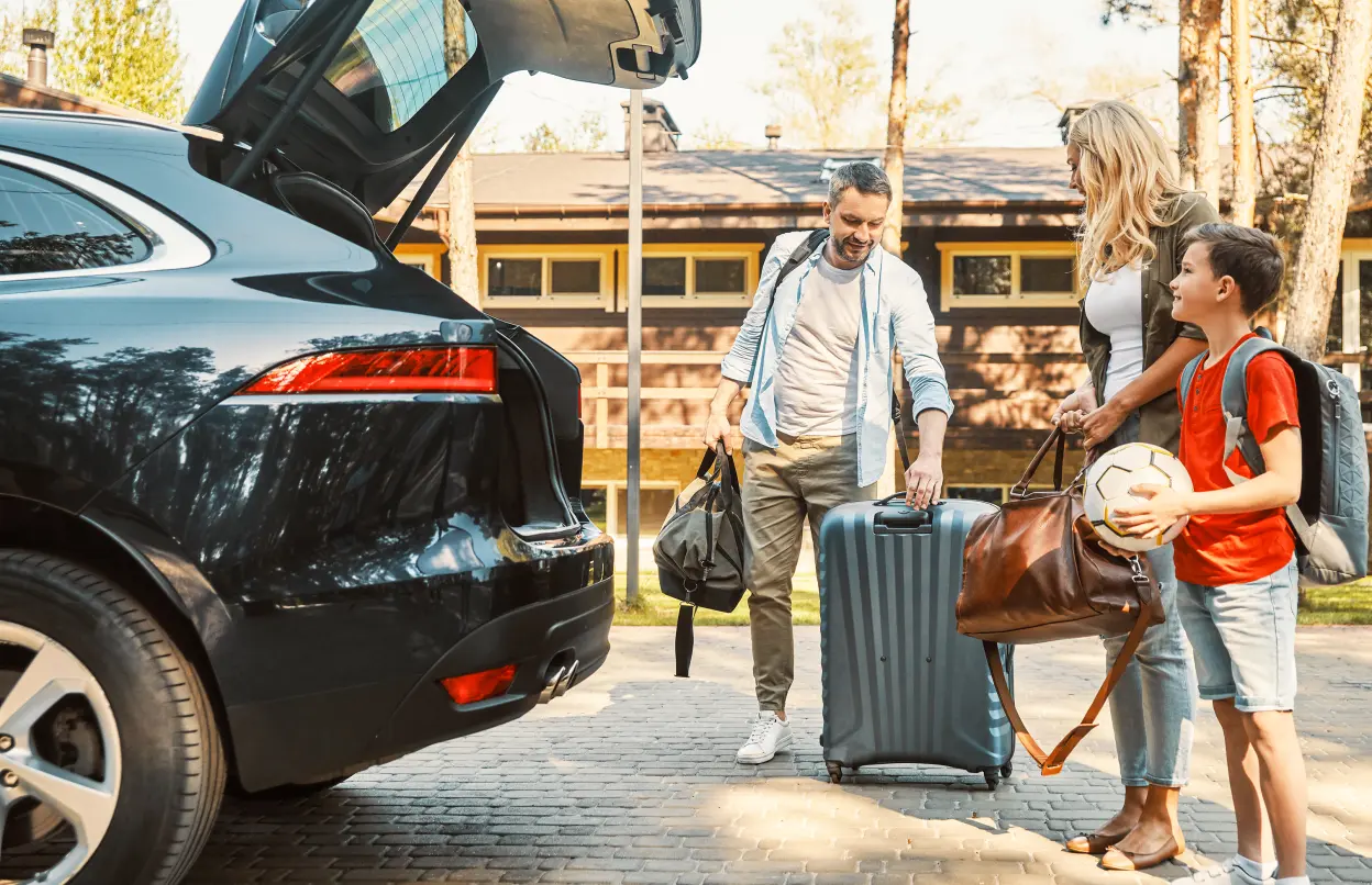 Familie lädt Gepäck in Kofferraum