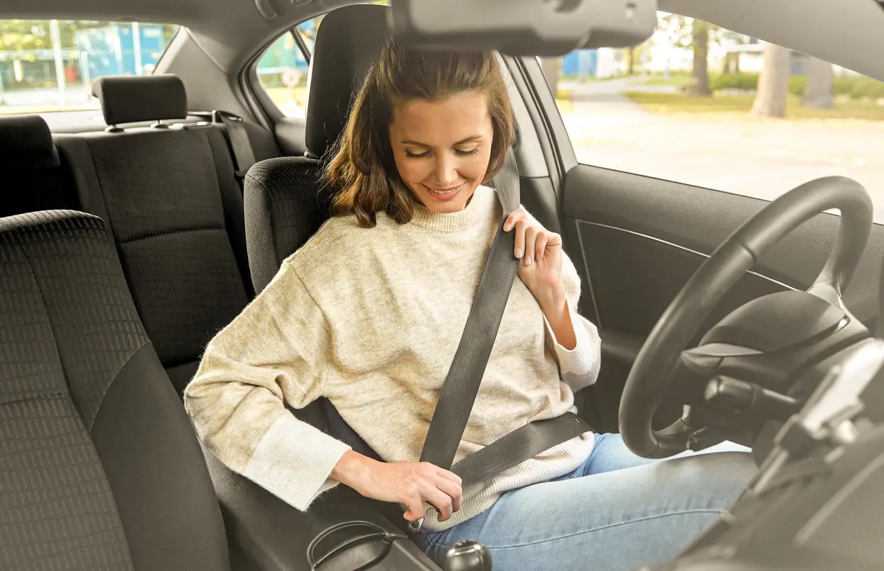Frau schnallt sich im Auto an