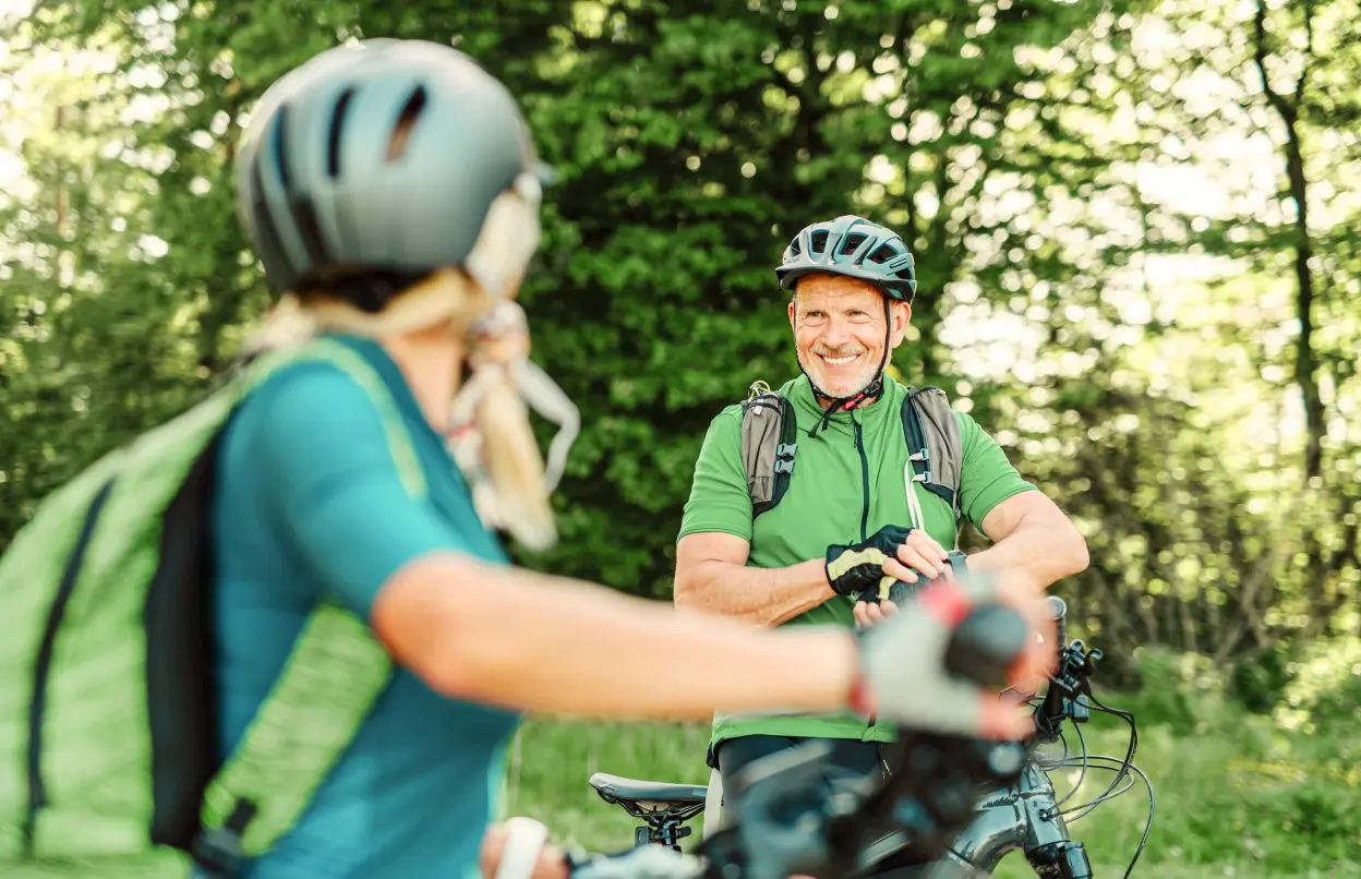Zwei Personen fahren mit dem E-Bike durch den Wald.