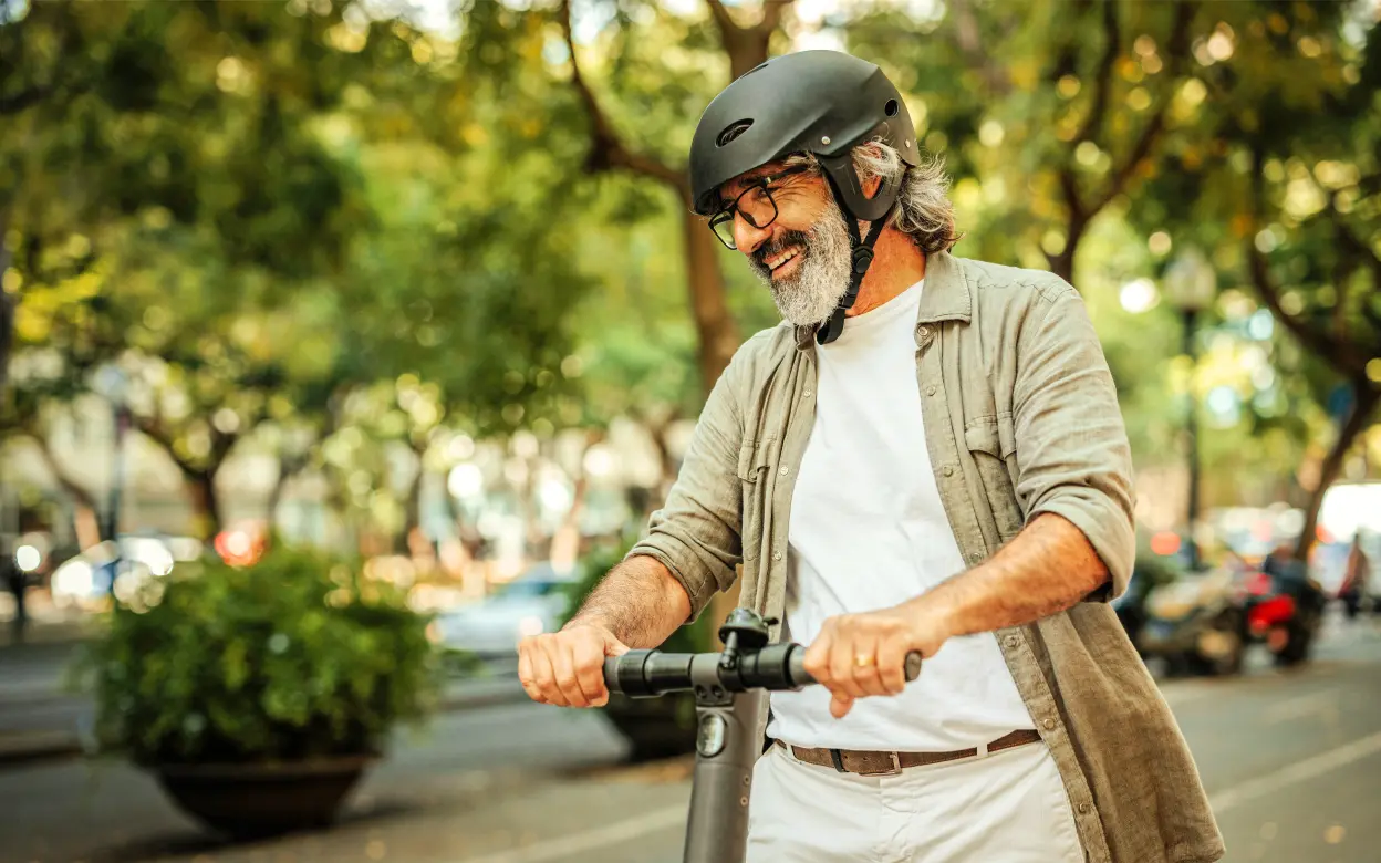 Ein Mann fährt lachend E-Scooter.