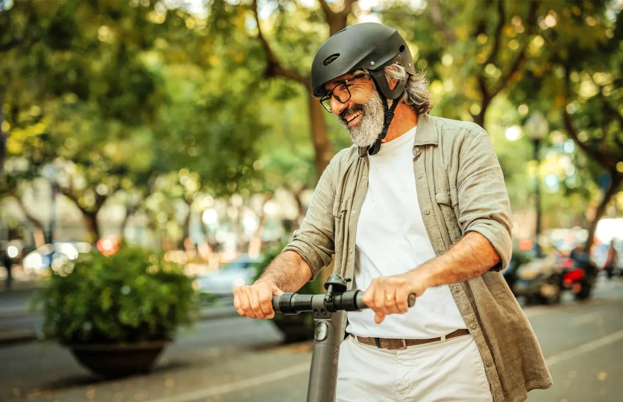 Ein Mann fährt lachend E-Scooter.