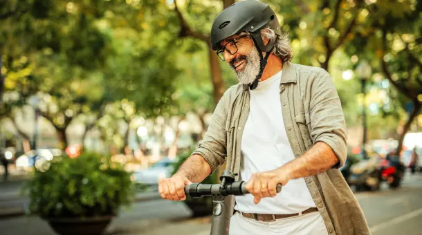 Ein Mann fährt lachend E-Scooter.