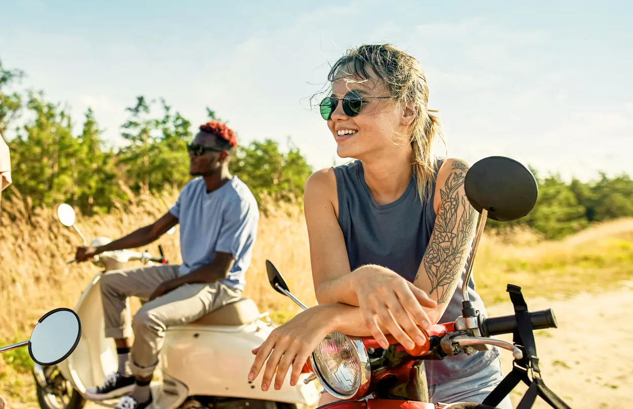 Drei Personen sitzen lächelnd auf Kleinkrafträdern.