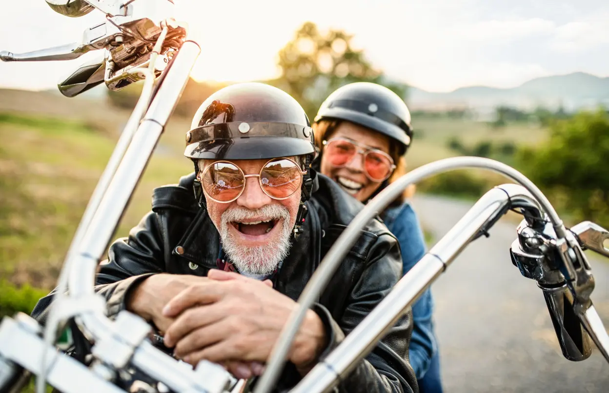 Ein lachendes Paar sitzt auf einem Motorrad.