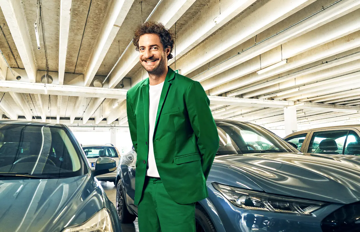 Ein Mann steht im Parkhaus und lacht.