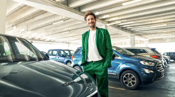 Ein Mann steht zufrieden im Parkhaus mit den Händen in den Hosentaschen.